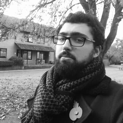 Portrait of a young man with glasses and a scarf outdoors in black and white.