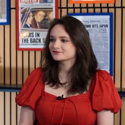 Young woman with dark hair in red dress during interview or discussion.