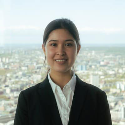 Professional woman in business attire with cityscape background.
