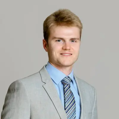 Professional young man in a light gray suit and blue shirt with striped tie.